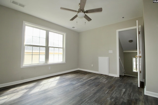 empty room featuring a wealth of natural light, ceiling fan, and dark wood-type flooring