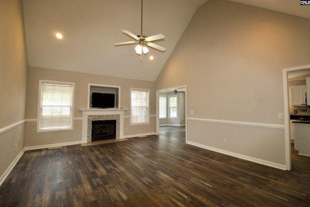 unfurnished living room with ceiling fan, high vaulted ceiling, a tiled fireplace, dark wood-style flooring, and baseboards