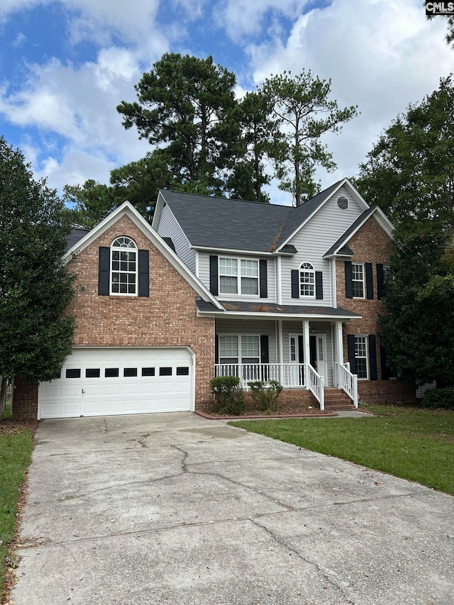 view of front of property featuring a front lawn, covered porch, and a garage