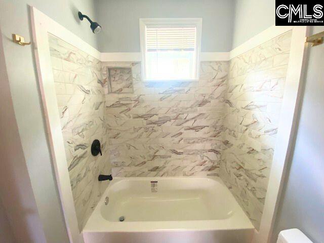 bathroom with tiled shower / bath combo and toilet