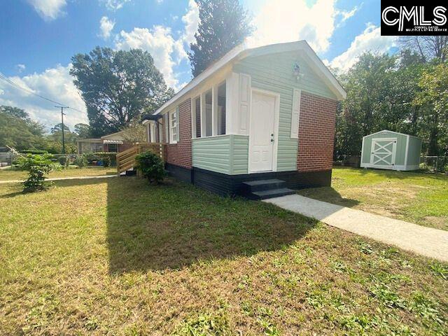 view of side of home with a lawn and a shed