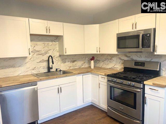 kitchen featuring stainless steel appliances, white cabinets, sink, and wooden counters