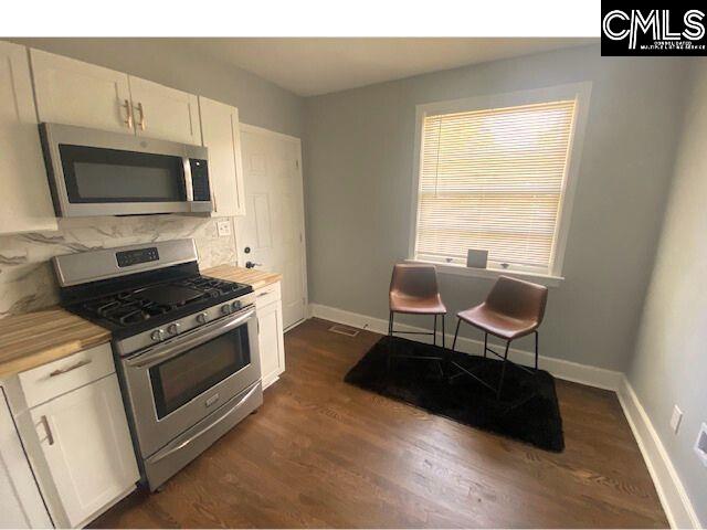 kitchen with white cabinetry, butcher block counters, stainless steel appliances, and dark hardwood / wood-style flooring