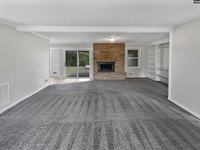 unfurnished living room with built in features, dark colored carpet, beamed ceiling, and a stone fireplace