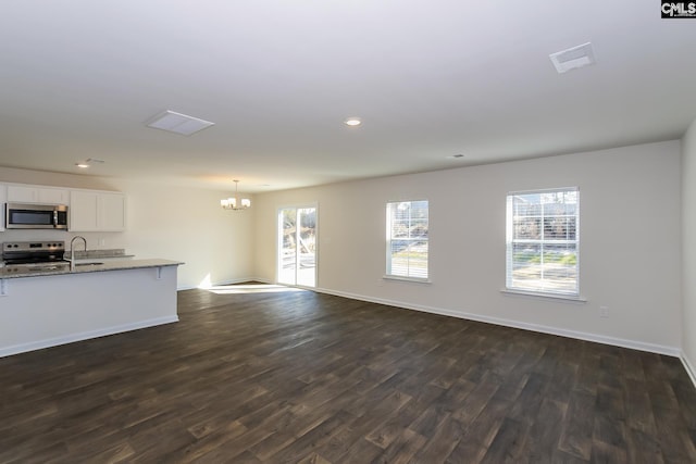 unfurnished living room featuring an inviting chandelier, sink, and dark wood-type flooring