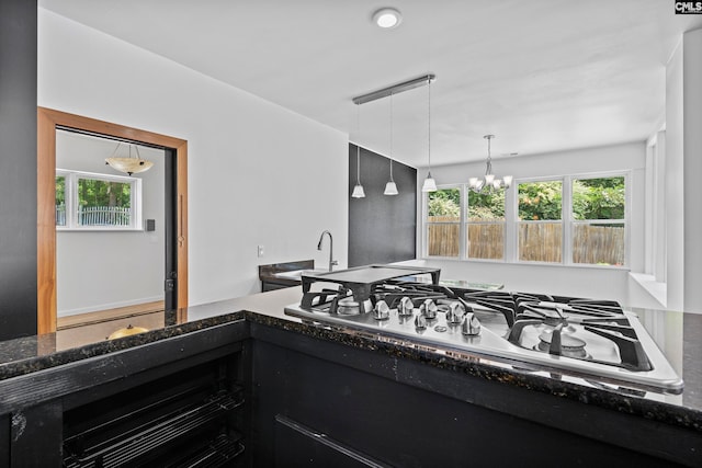 kitchen featuring dark stone countertops, pendant lighting, white gas cooktop, and a chandelier