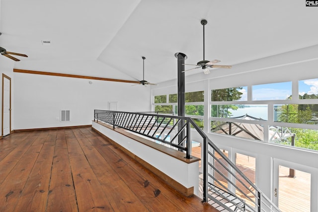 corridor featuring a wealth of natural light, vaulted ceiling, and dark hardwood / wood-style flooring