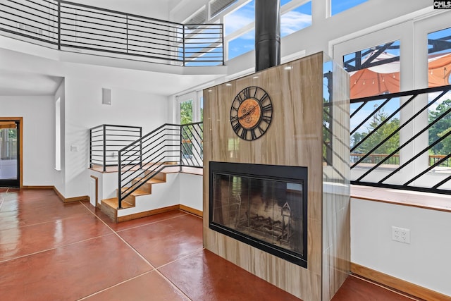 stairway featuring a towering ceiling, a wealth of natural light, and concrete floors