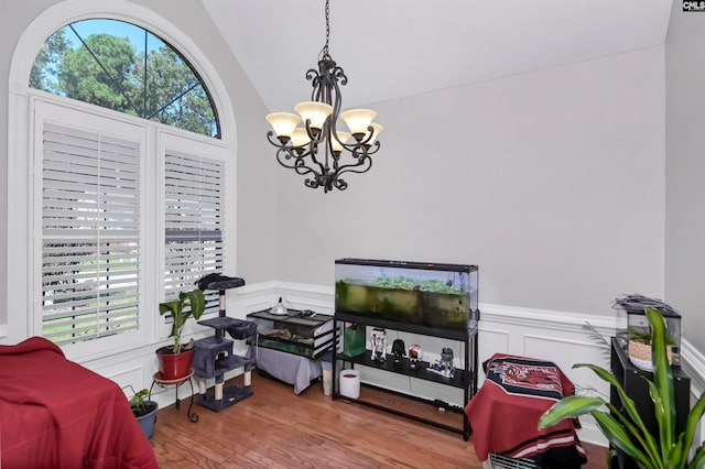 interior space with a notable chandelier, lofted ceiling, and hardwood / wood-style flooring