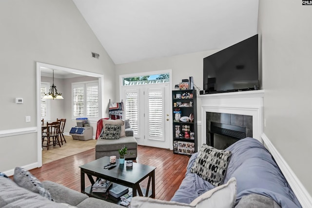 living room with high vaulted ceiling, a chandelier, hardwood / wood-style flooring, and a fireplace