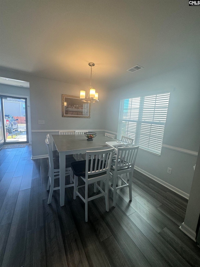 dining area with a chandelier, dark wood-type flooring, and a wealth of natural light