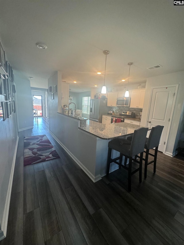 kitchen featuring hanging light fixtures, kitchen peninsula, white cabinetry, appliances with stainless steel finishes, and dark hardwood / wood-style flooring