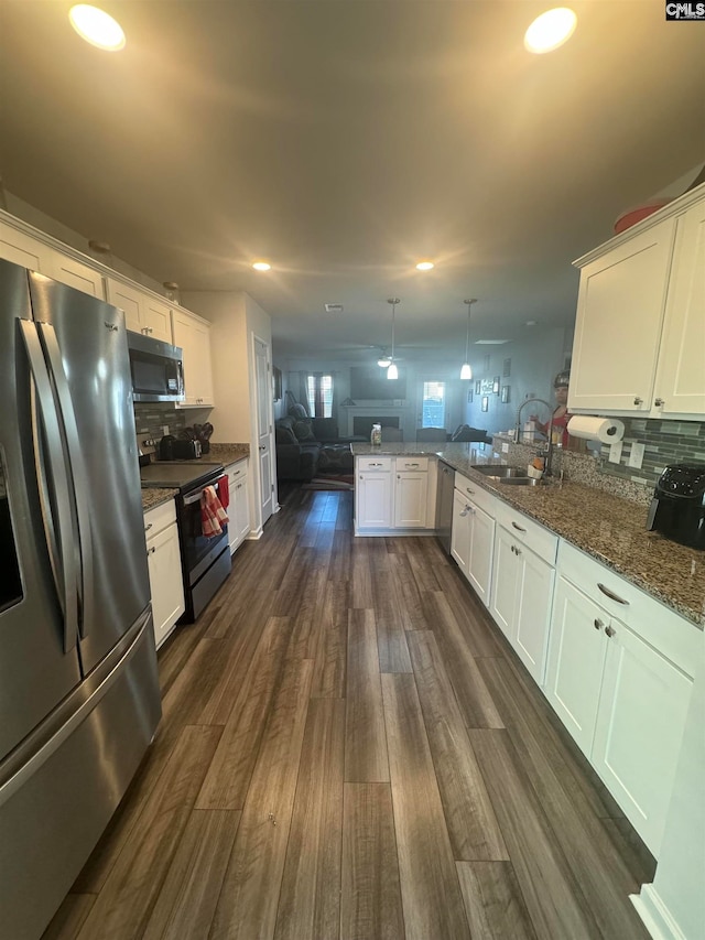 kitchen with dark hardwood / wood-style floors, stainless steel appliances, kitchen peninsula, white cabinetry, and decorative light fixtures