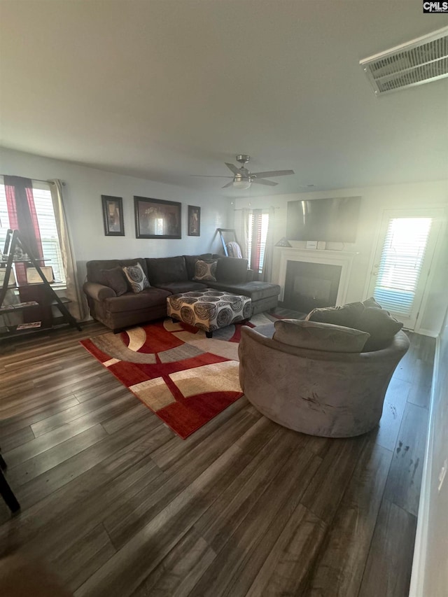 living room featuring ceiling fan and dark wood-type flooring