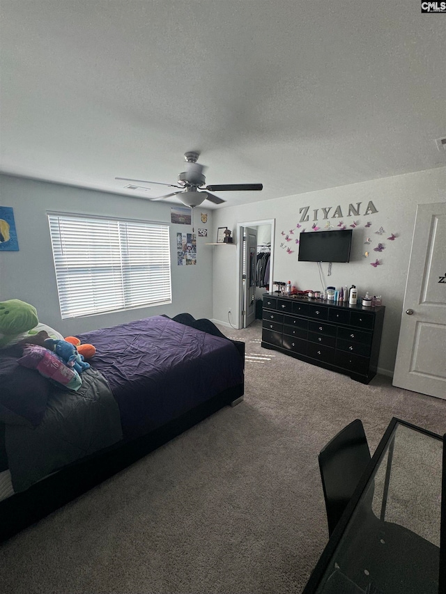 carpeted bedroom with a spacious closet, ceiling fan, a closet, and a textured ceiling