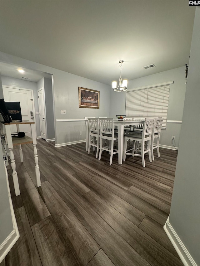 dining area with a chandelier and dark wood-type flooring