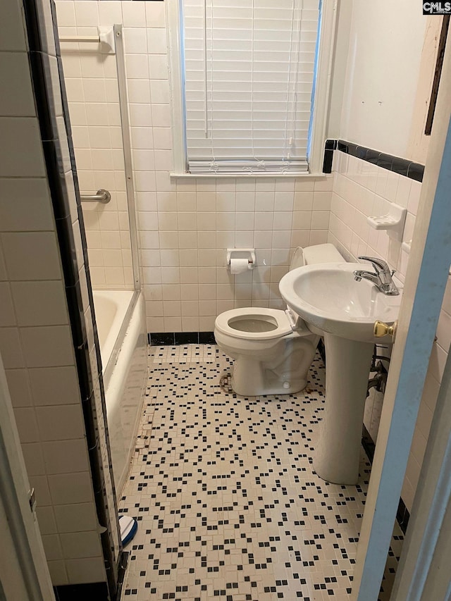 bathroom featuring toilet, tile patterned flooring, and tile walls