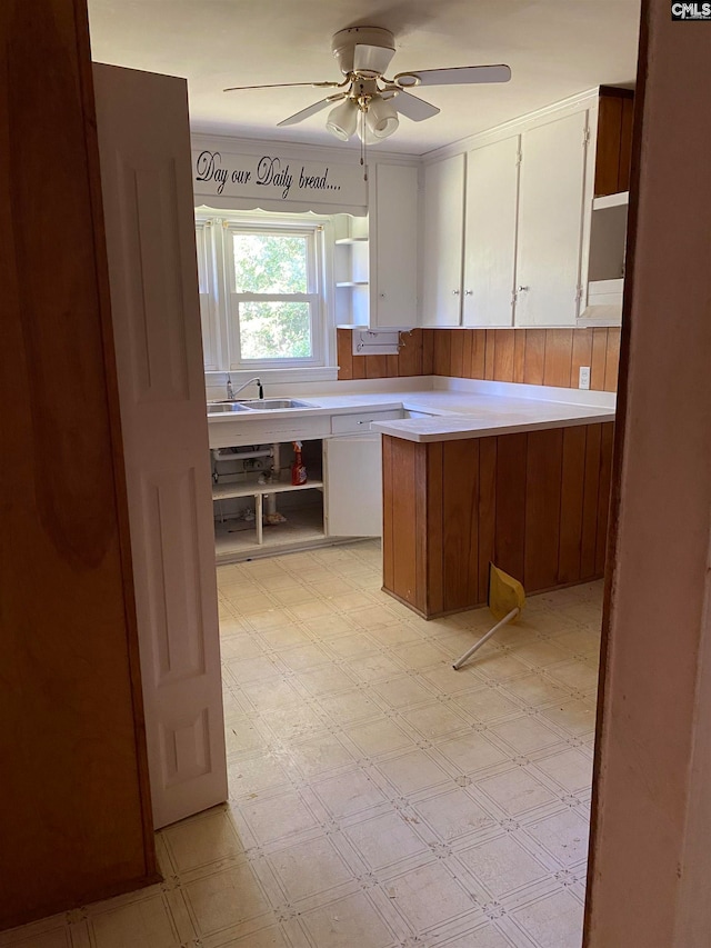 kitchen featuring ceiling fan, sink, kitchen peninsula, and white cabinetry