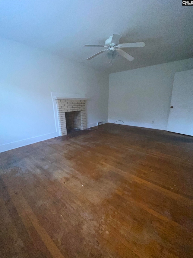 unfurnished living room with a fireplace, dark hardwood / wood-style flooring, and ceiling fan