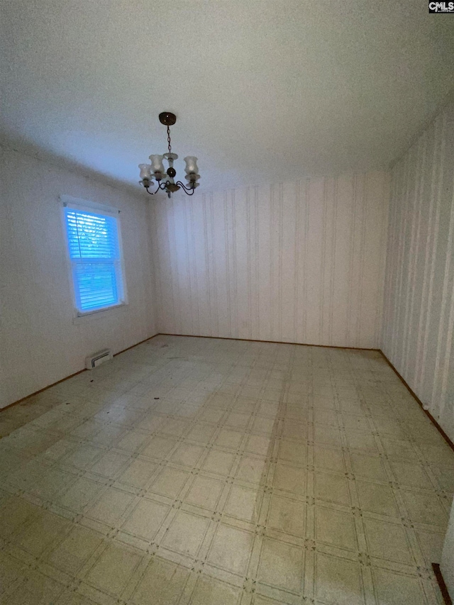 unfurnished room with a textured ceiling and a chandelier