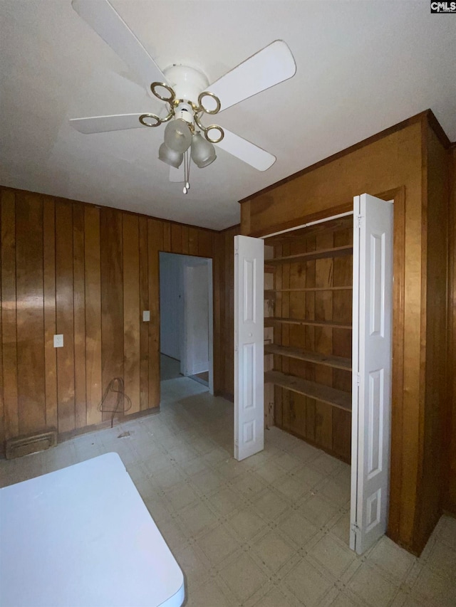 empty room with ceiling fan and wood walls