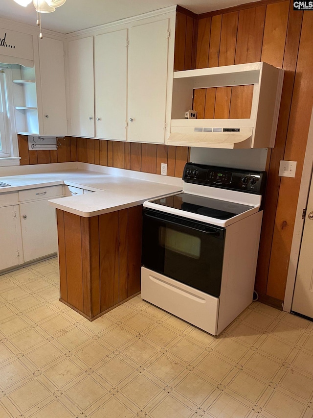 kitchen with kitchen peninsula, white electric range oven, exhaust hood, and white cabinets