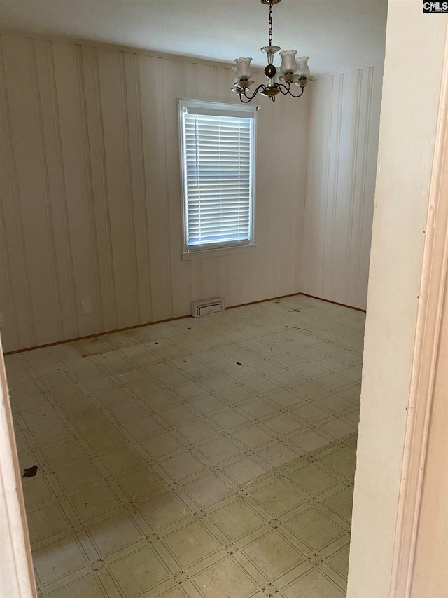 unfurnished room with a chandelier