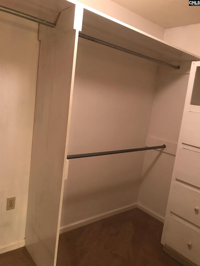 walk in closet featuring dark carpet