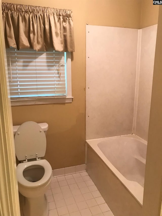 bathroom with tile patterned floors, a tub to relax in, and toilet