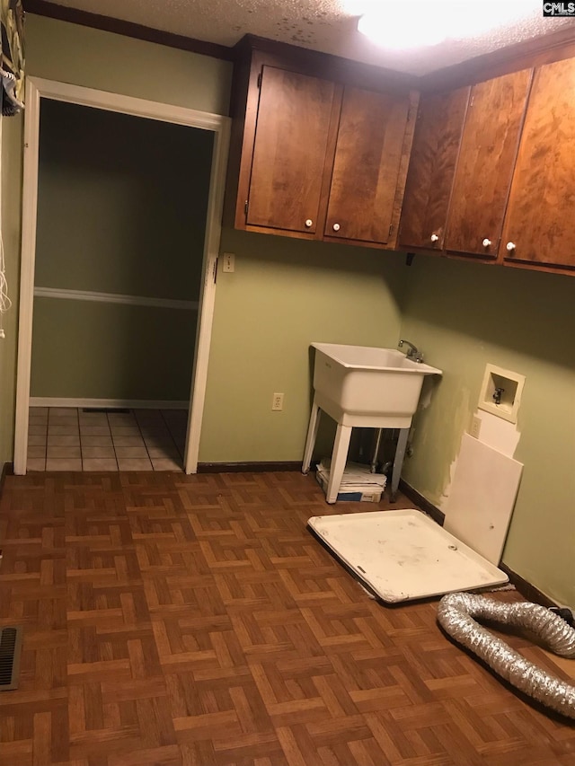 washroom with hookup for a washing machine, sink, dark parquet flooring, cabinets, and a textured ceiling