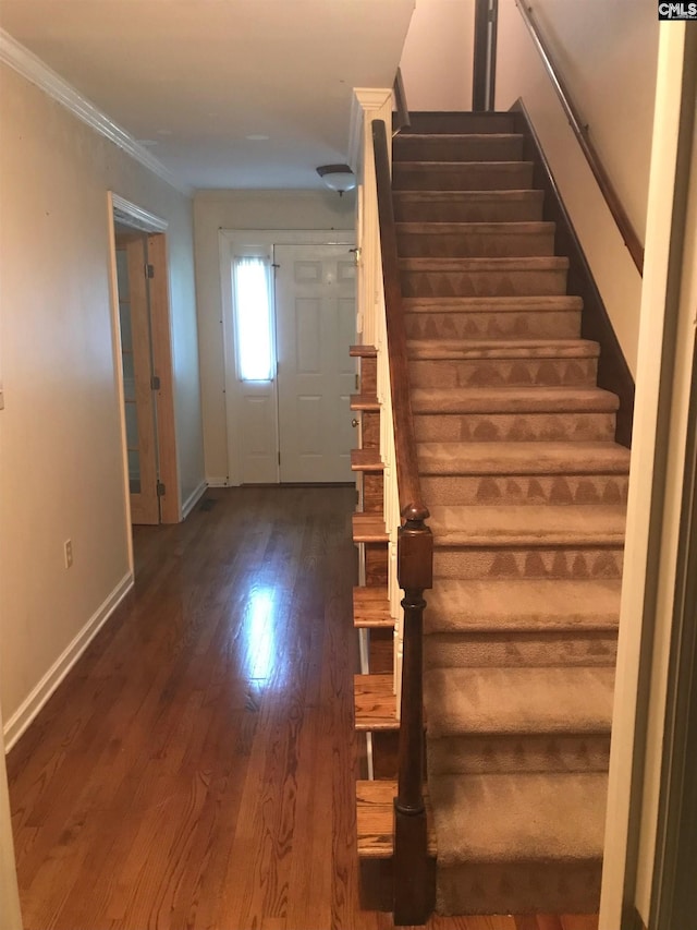 staircase featuring wood-type flooring and ornamental molding