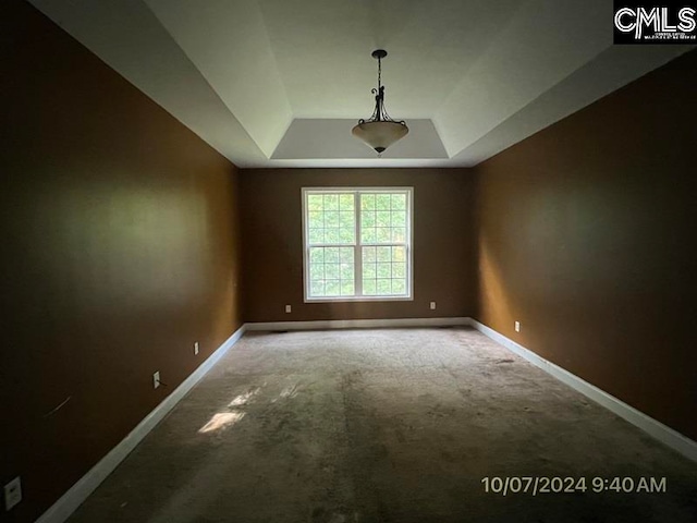 carpeted empty room with a raised ceiling