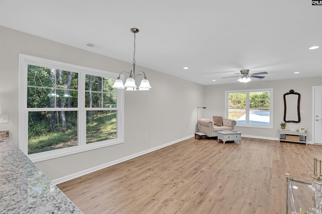 living area featuring wood-type flooring and ceiling fan with notable chandelier