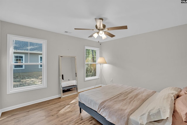 bedroom with light wood-type flooring, multiple windows, and ceiling fan