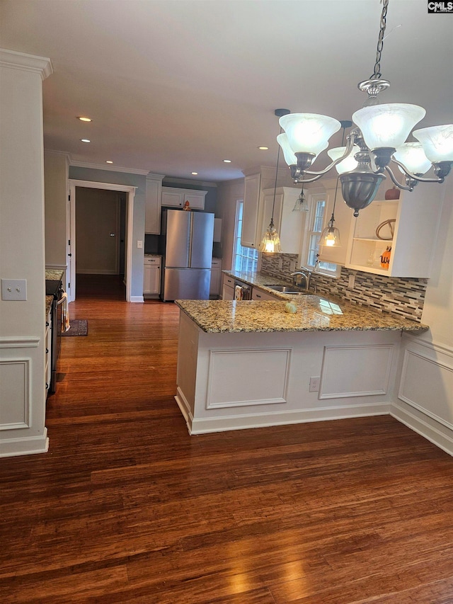 kitchen featuring appliances with stainless steel finishes, kitchen peninsula, hanging light fixtures, and dark hardwood / wood-style floors