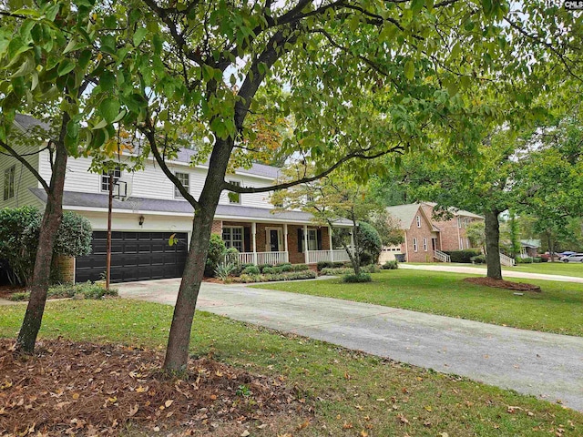 view of front of property featuring a front lawn, covered porch, and a garage