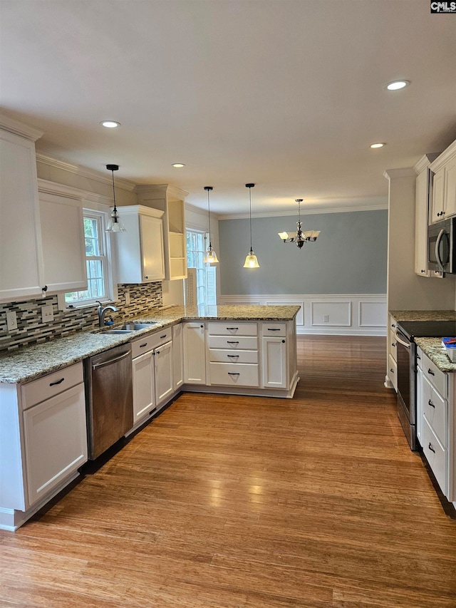 kitchen with hanging light fixtures, kitchen peninsula, white cabinetry, stainless steel appliances, and light hardwood / wood-style floors