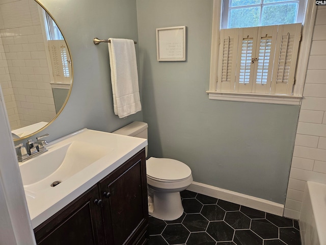 bathroom featuring tile patterned flooring, a tub to relax in, vanity, and toilet