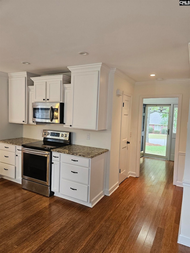 kitchen with ornamental molding, stainless steel appliances, dark wood-type flooring, and white cabinetry