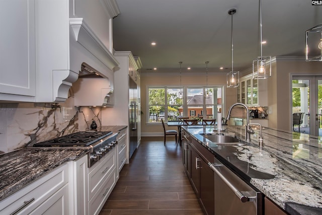 kitchen with white cabinets, hanging light fixtures, sink, appliances with stainless steel finishes, and dark stone counters