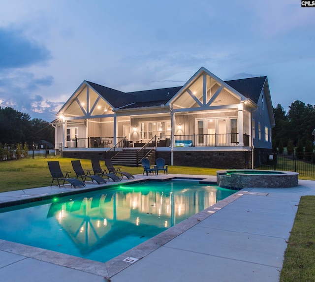 pool at dusk featuring an in ground hot tub, a lawn, and a patio area