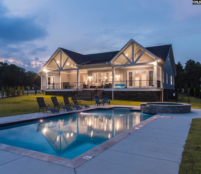 pool at dusk with an in ground hot tub, a patio, and a yard