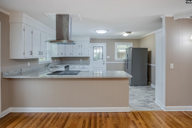 kitchen with island exhaust hood, light wood-type flooring, stainless steel fridge, and kitchen peninsula