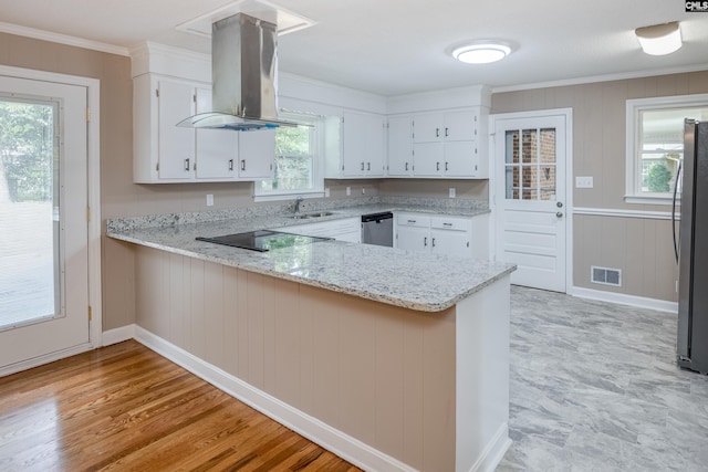 kitchen featuring kitchen peninsula, island range hood, light stone countertops, and white cabinets