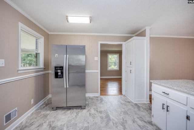 kitchen with crown molding, stainless steel fridge, and white cabinetry