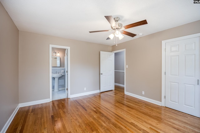 unfurnished bedroom featuring light wood-type flooring, ceiling fan, ensuite bathroom, and sink