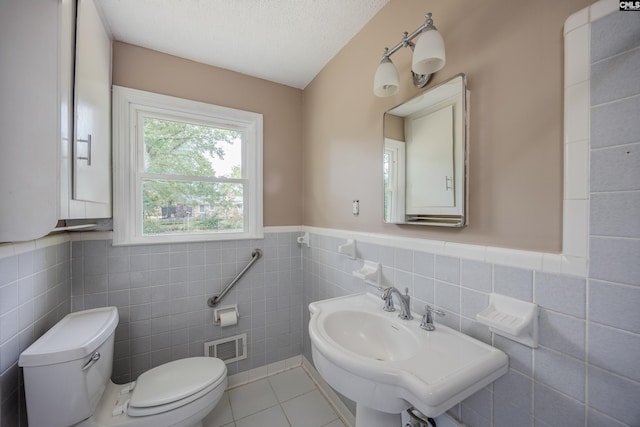 bathroom featuring tile patterned flooring, tile walls, toilet, and a textured ceiling