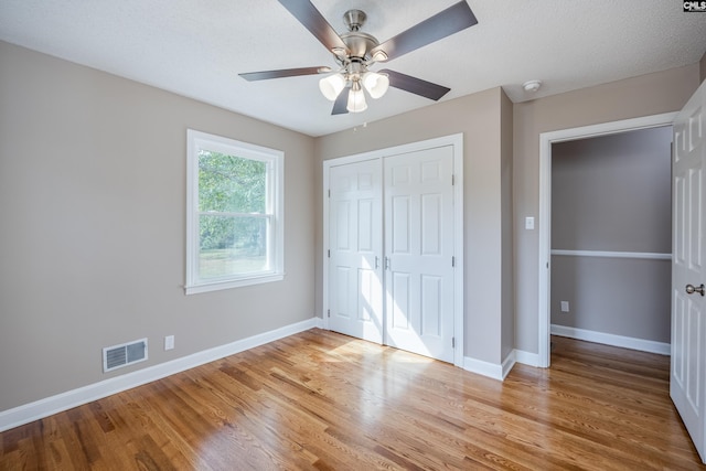 unfurnished bedroom with a closet, light hardwood / wood-style floors, a textured ceiling, and ceiling fan