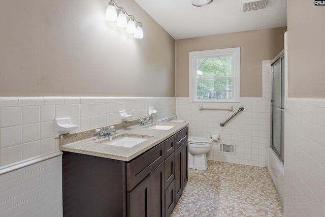 full bathroom featuring enclosed tub / shower combo, vanity, toilet, tile walls, and tile patterned flooring