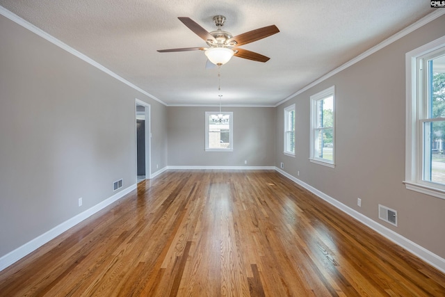 spare room featuring ornamental molding, ceiling fan with notable chandelier, plenty of natural light, and light hardwood / wood-style floors